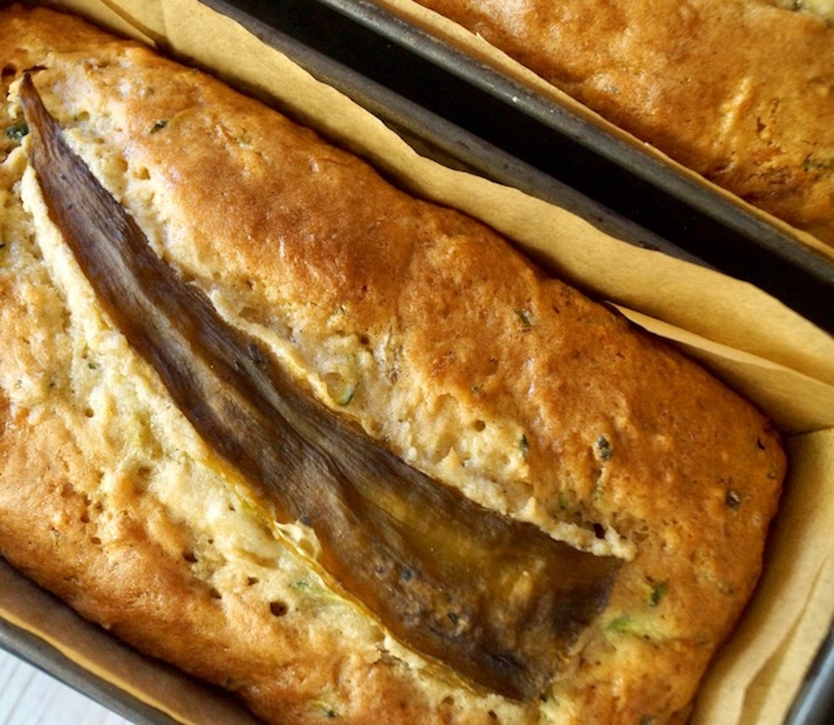 Baked loaf of gluten-free zucchini bread with a hatch chile pepper baked into the top.