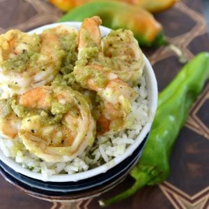 White bowl with rice and shrimp with green sauce on top.