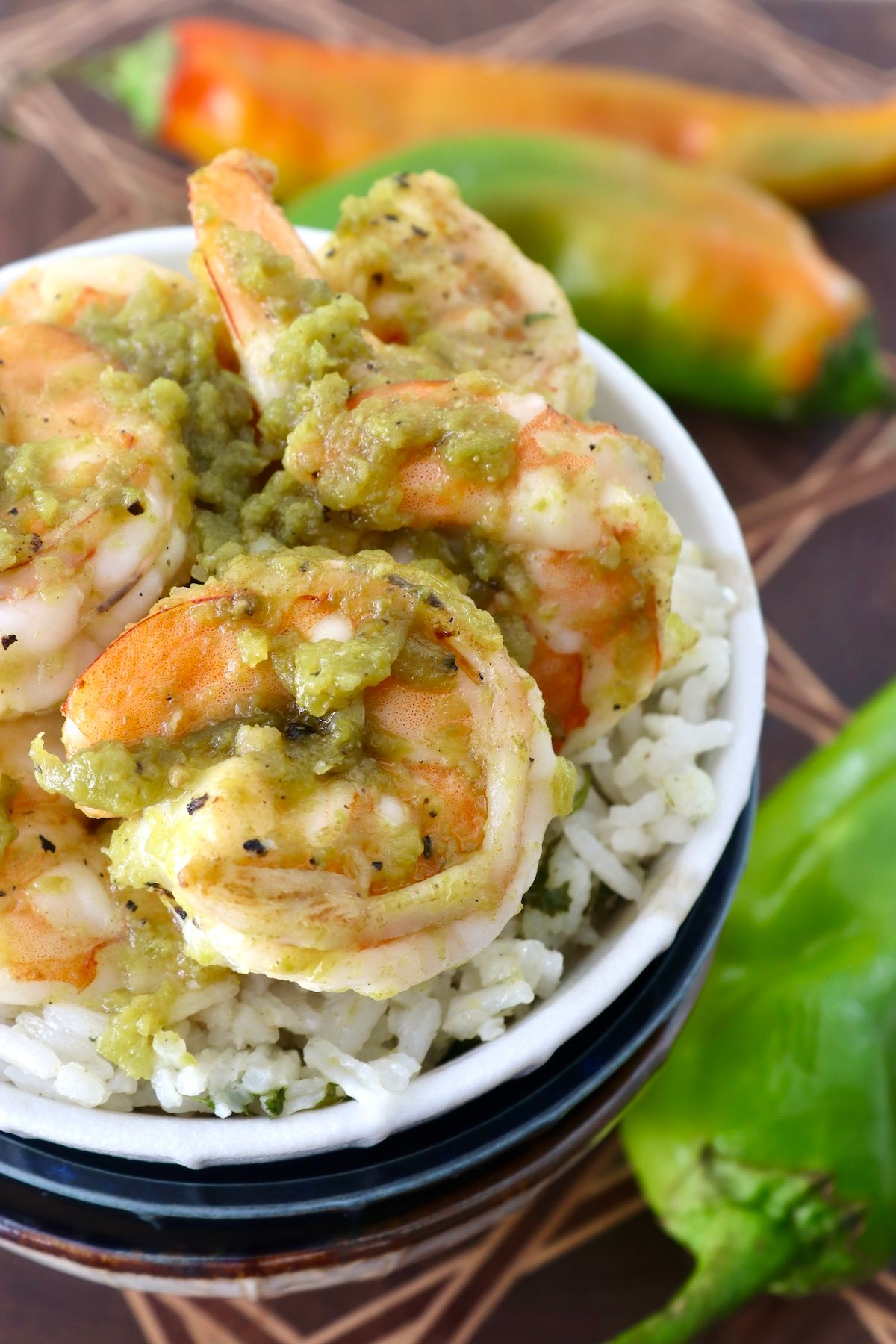 White bowl with rice and shrimp with green sauce on top.
