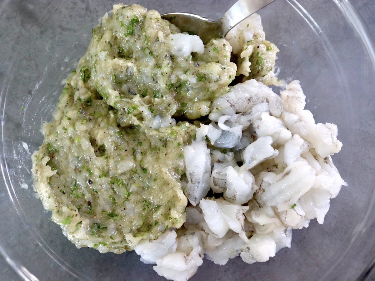 Paste-like mixture of shrimp and cilantro with chunks of shrimp next to it in a glass bowl.