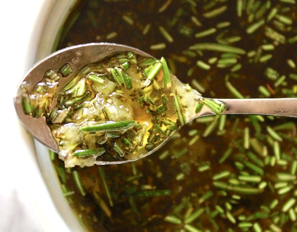 Spoonful of olive oil with chopepd rosemary and basil.