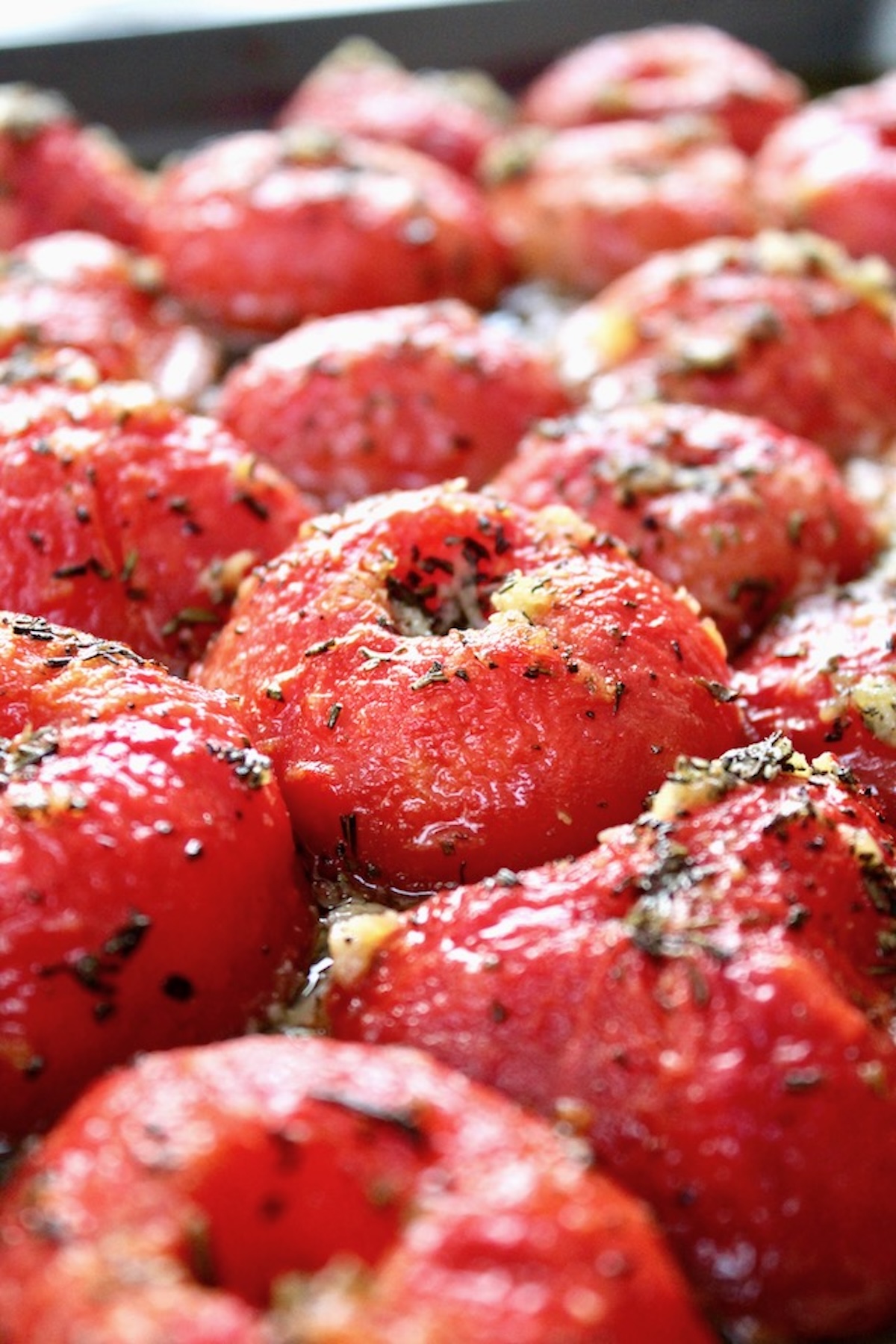 Slow roasted tomato confit with bits of rosemary on a sheet pan - about half way done.