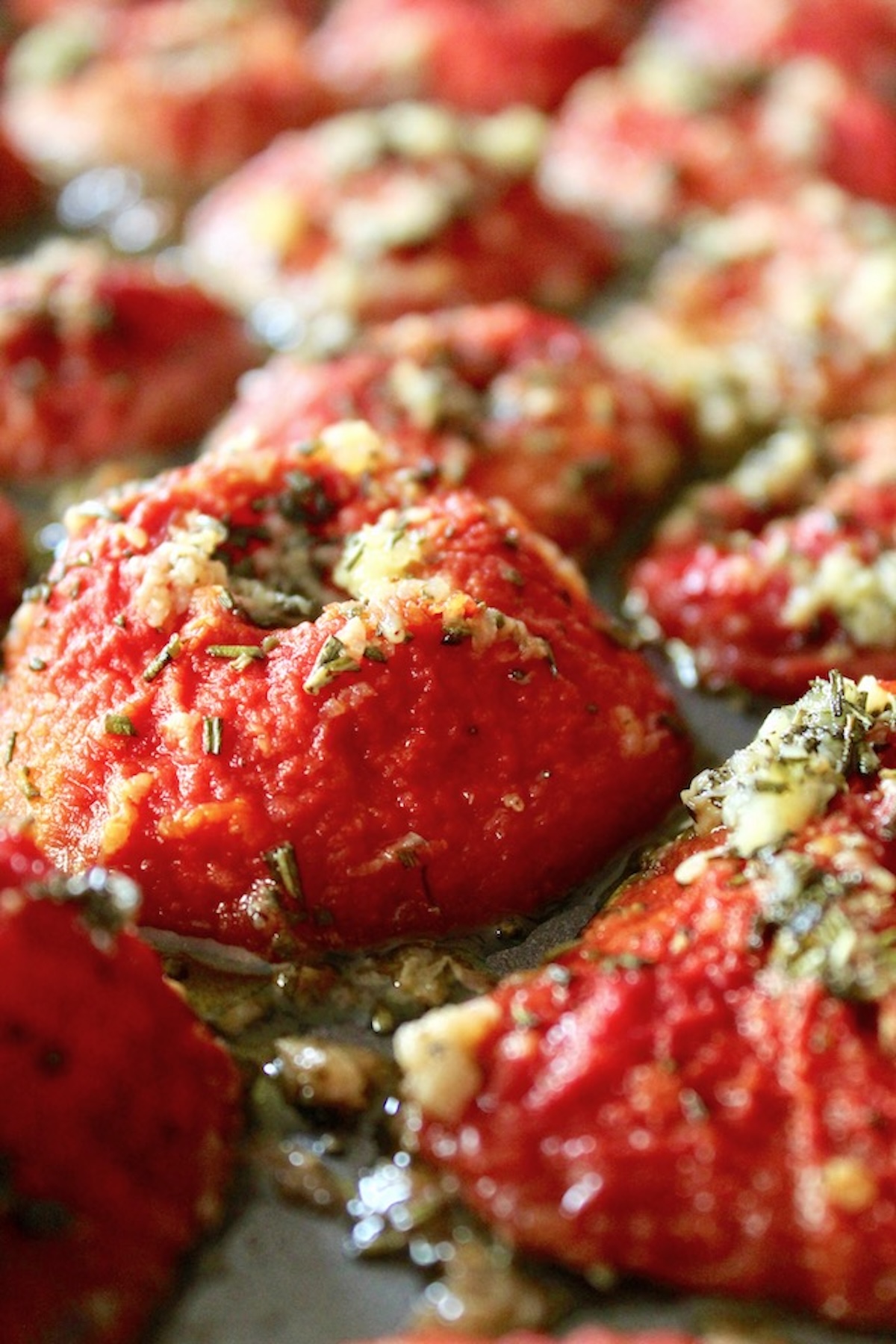 Slow roasted tomato confit with bits of rosemary on a sheet pan,