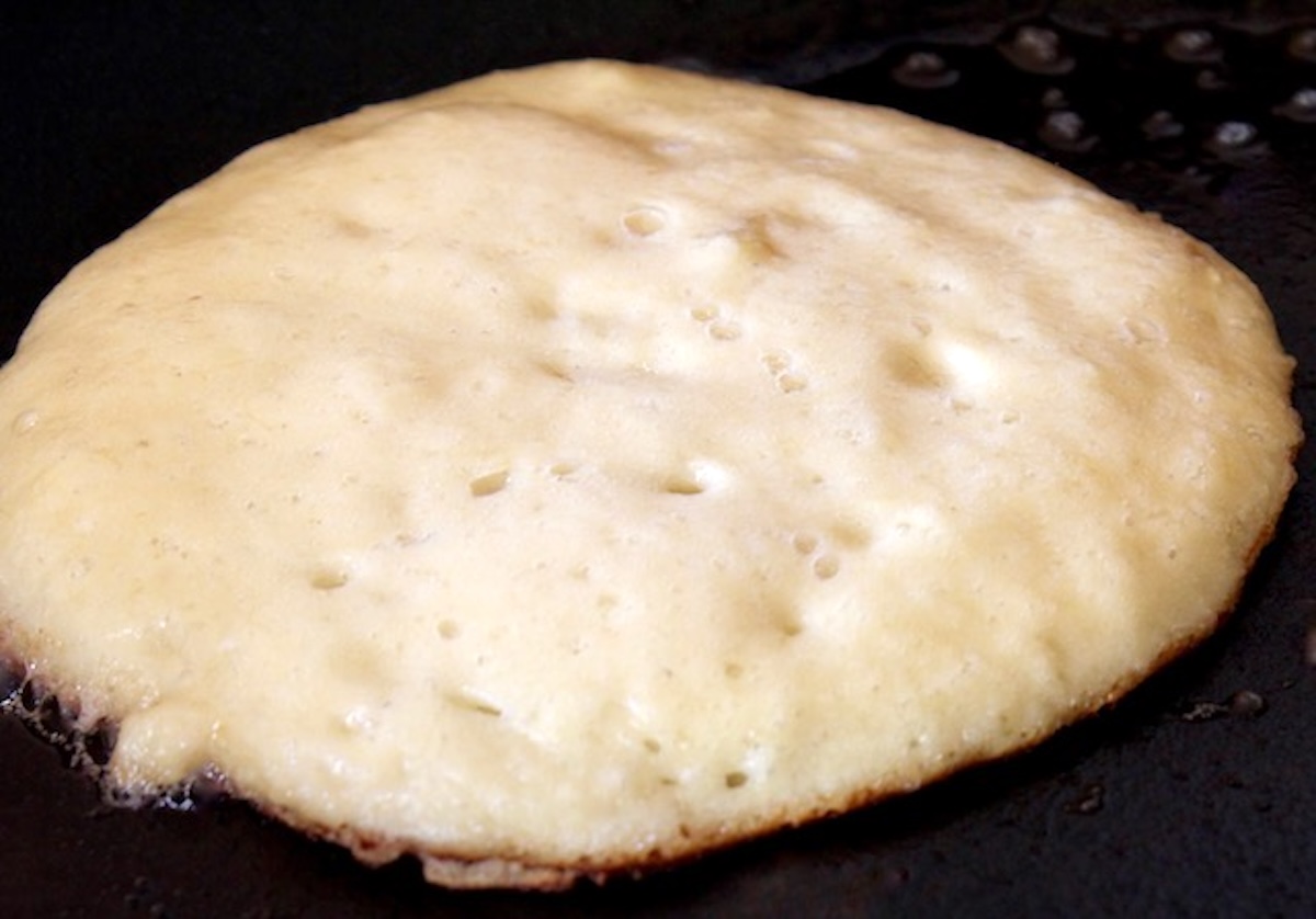 Coconut flour pancake in pan with only bottom side cooked.