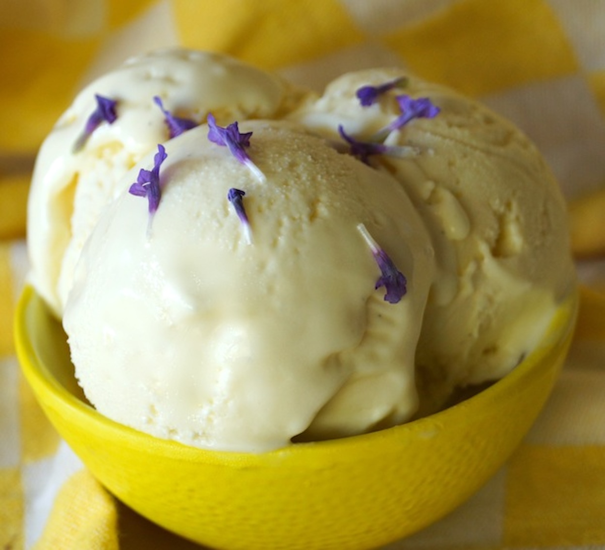 Lavender-Lemon-Frozen-Custard-Recipe Three scoops of frozen custard with lemon and lavender in yellow bowl.