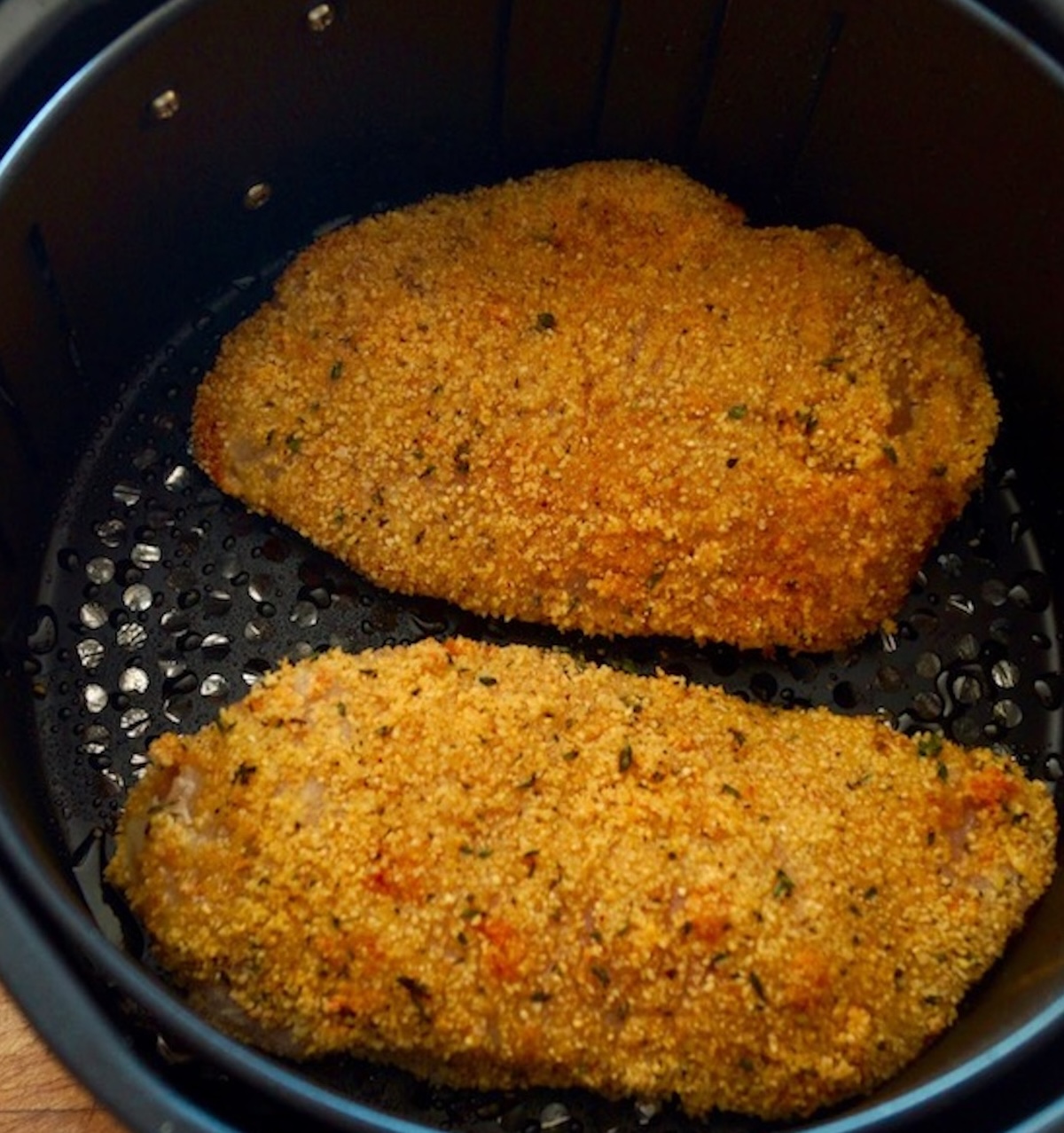 Air-Fryer-Fried-Chicken (Gluten-Free) Two cooked breaded chicken breasts in an air fryer basket.