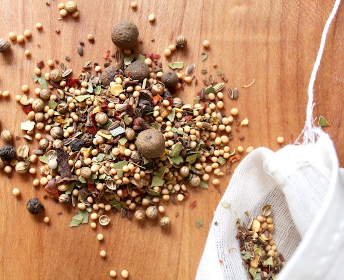 Pickling spices on a light wood cutting board.
