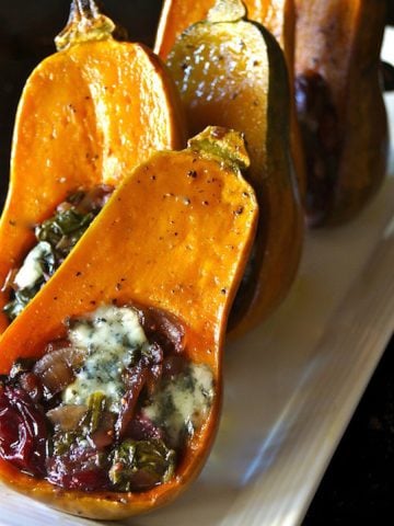 A few Caramelized Onion-Bacon & Cranberry Honeynut Squash on a narrow white plate, resting upright.