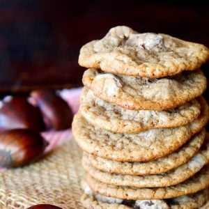 Tall stack of Chestnut Cookies with chocolate chips on raw chestnuts next to them