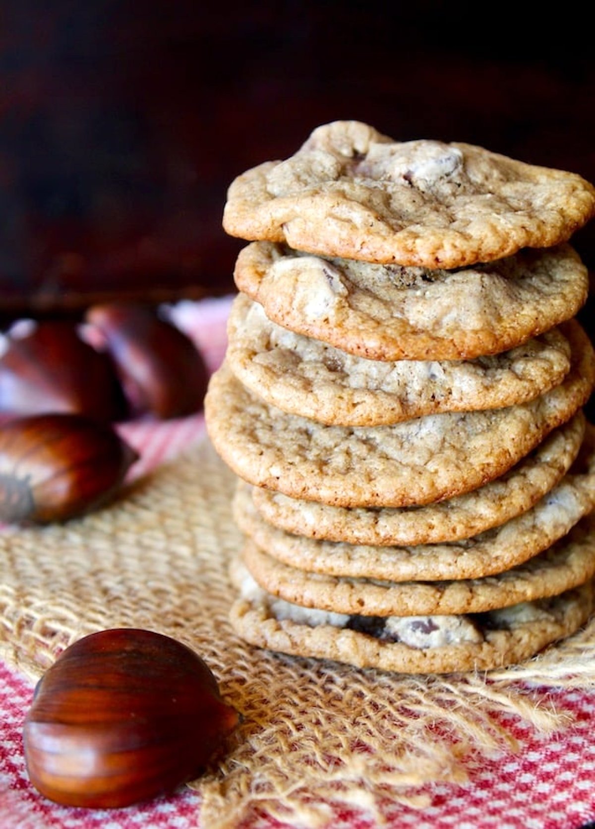 tall stack of Chestnut Cookies with chocolate chips on raw chestnuts next to them