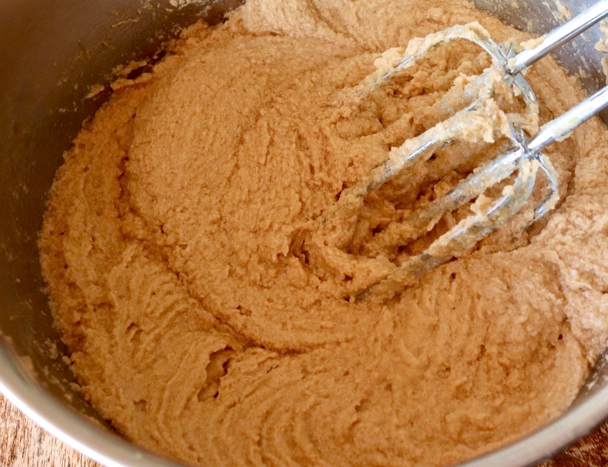 Stainless steel bowl with smooth chestnut cookie batter and two electric beaters.