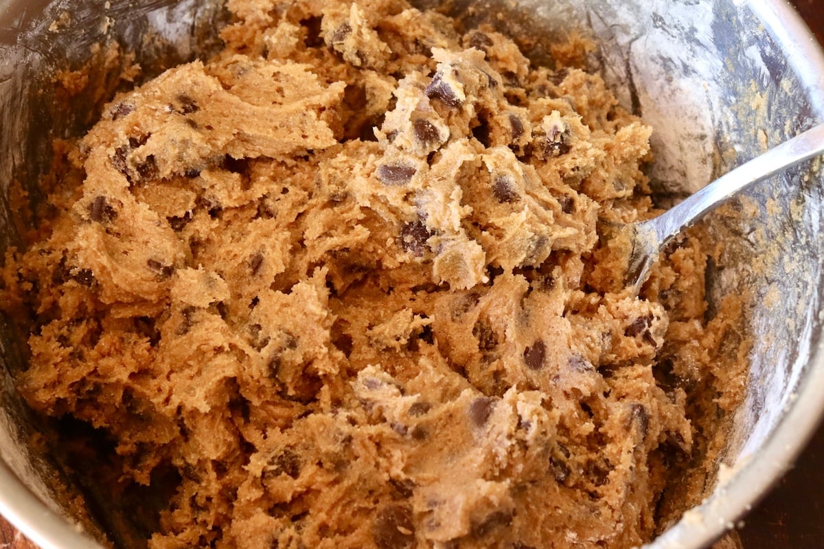 Chestnut chocolate chip cookie batter with a spoon in a large bowl.