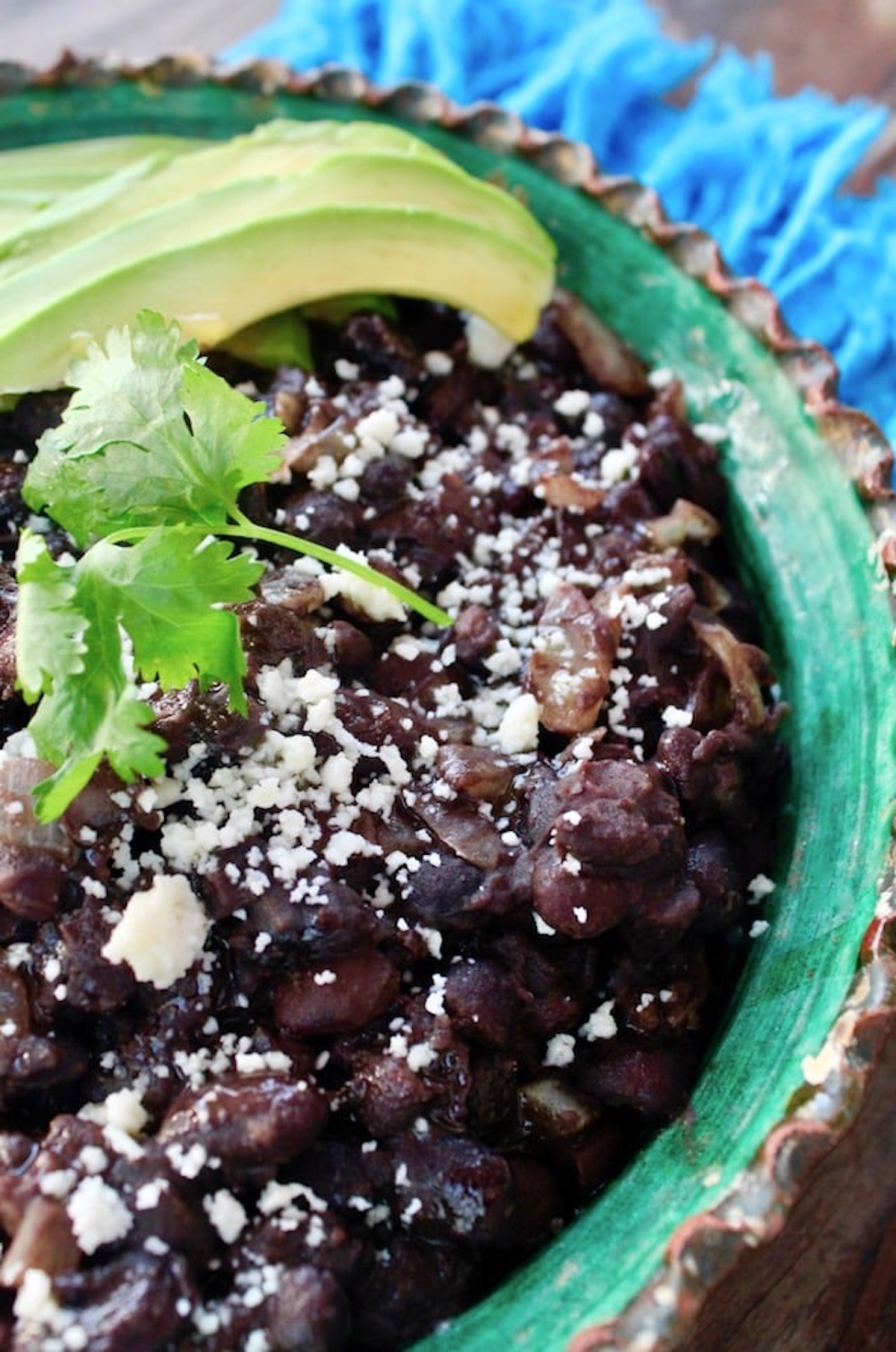 Mexican Black Beans made from scratch in green-painted terra cotta bowl with crimped edges.