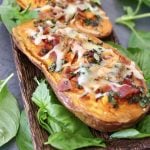 One baked sweet potato half with bacon, basil and melted cheese on top.