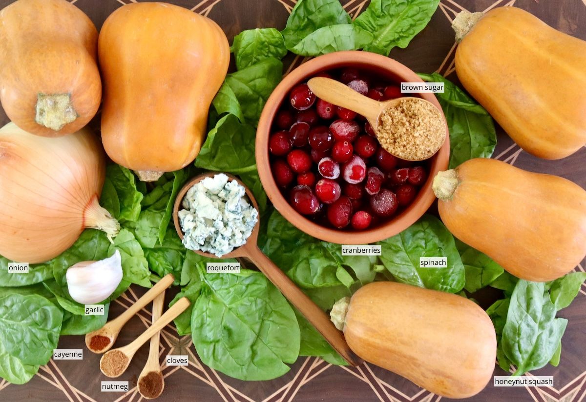 Ingredients for stuffed honeynut squash including spinach a few squash, roquefort cheese, cranberries and spices.
