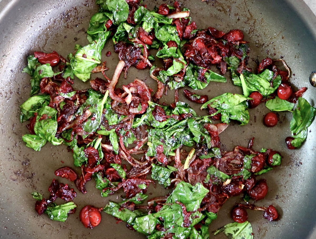 Caramelized onions, cooked cranberries iand wilted spinach n a skillet. 