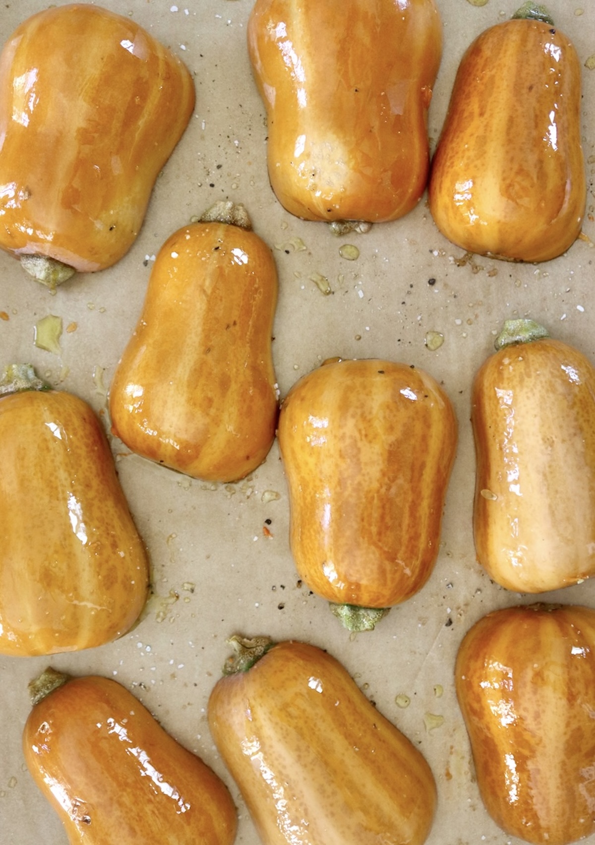 Several halved honeynut squash, round side up, on a a prchment-lined sheet pan.