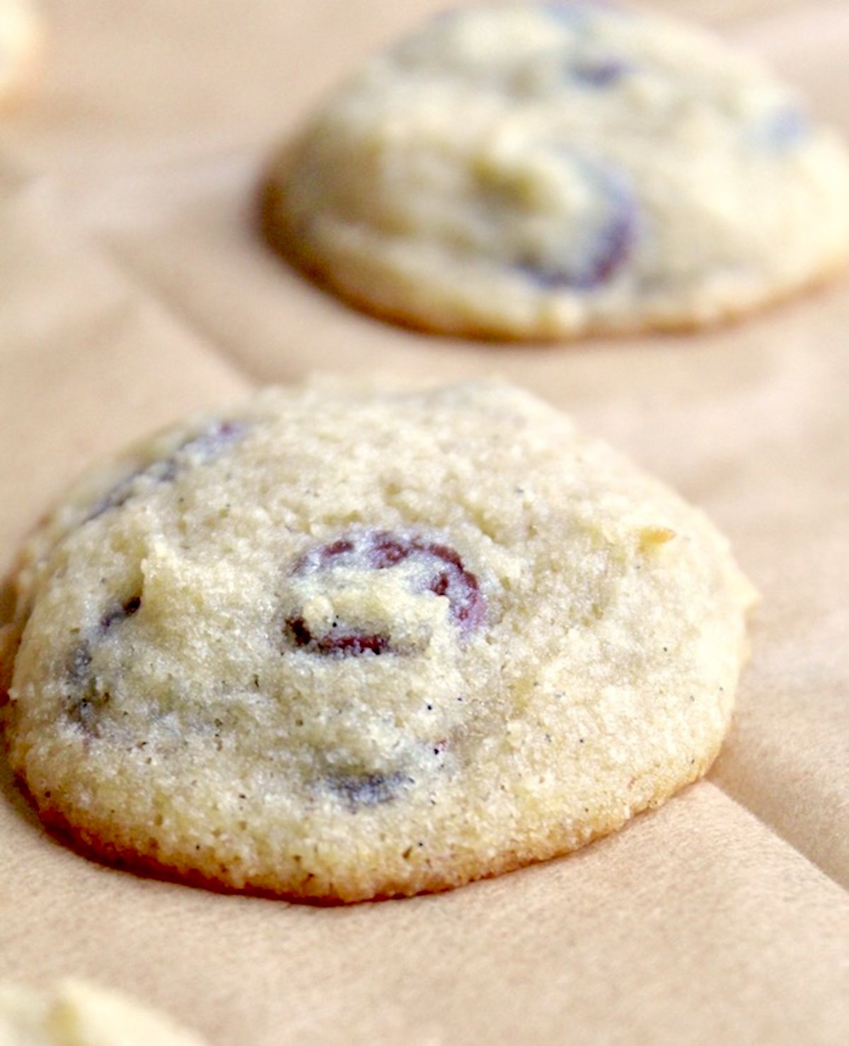 2 baked coconut chocolate chip cookies on parchment paper.
