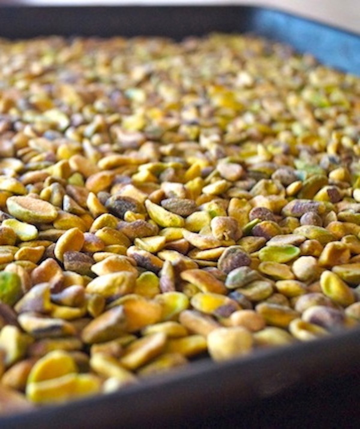 Roasted pistachios on a baking sheet.
