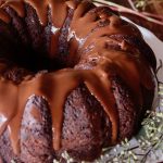 One whole gluten-free chocolate cake with chocolate glaze dripping down the sides.