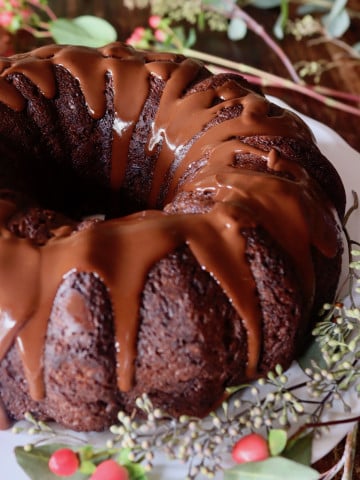 One whole gluten-free chocolate cake with chocolate glaze dripping down the sides.