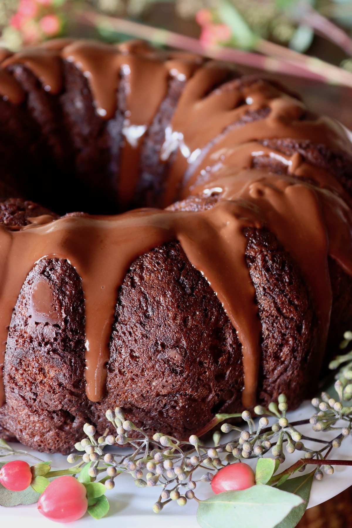 Close up of one whole gluten-free chocolate cake with chocolate glaze dripping down the sides.