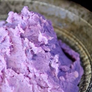 Mashed purple sweet potatoes in a black bowl