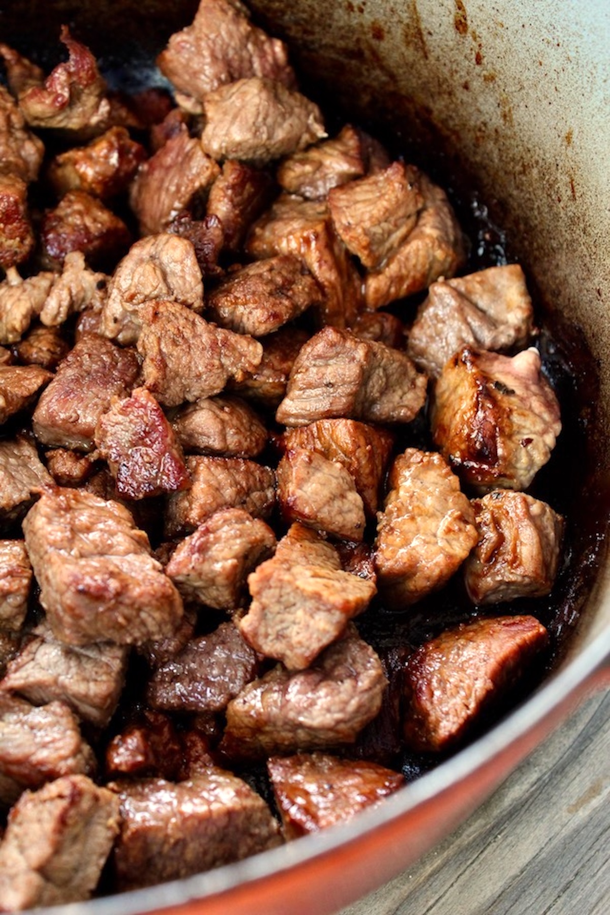Dutch oven filled with seared and cubed stew meat.