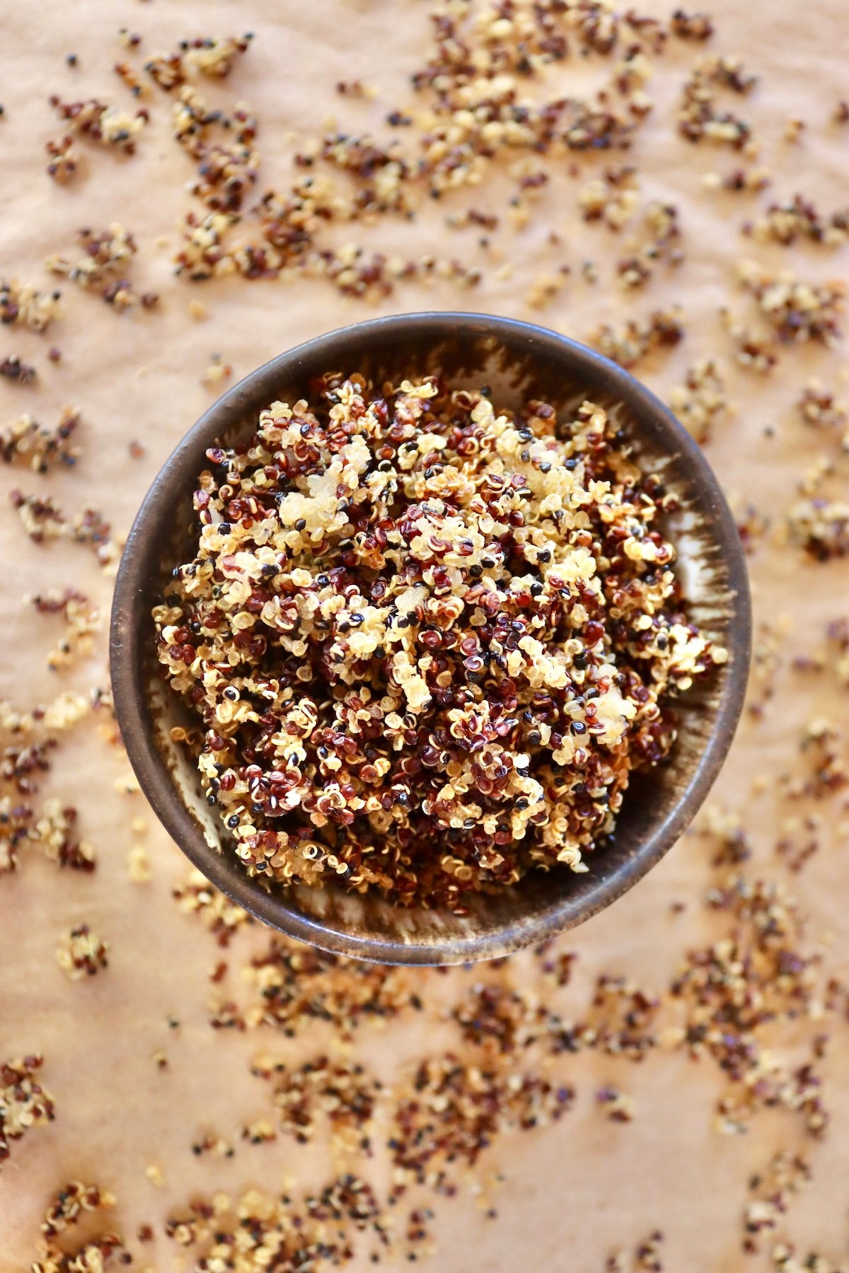 Top view of a brown-rimmed bowl filled iwth crisped quinoa.