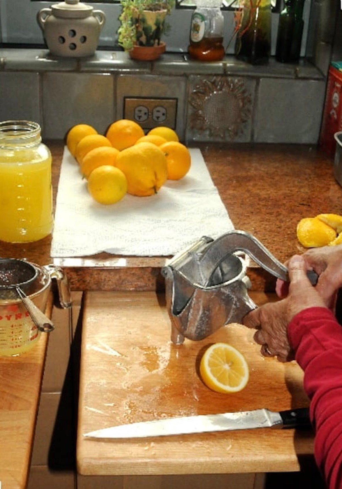 Several lemons on paper towels and a lemon being juiced with old-fashioned juice.