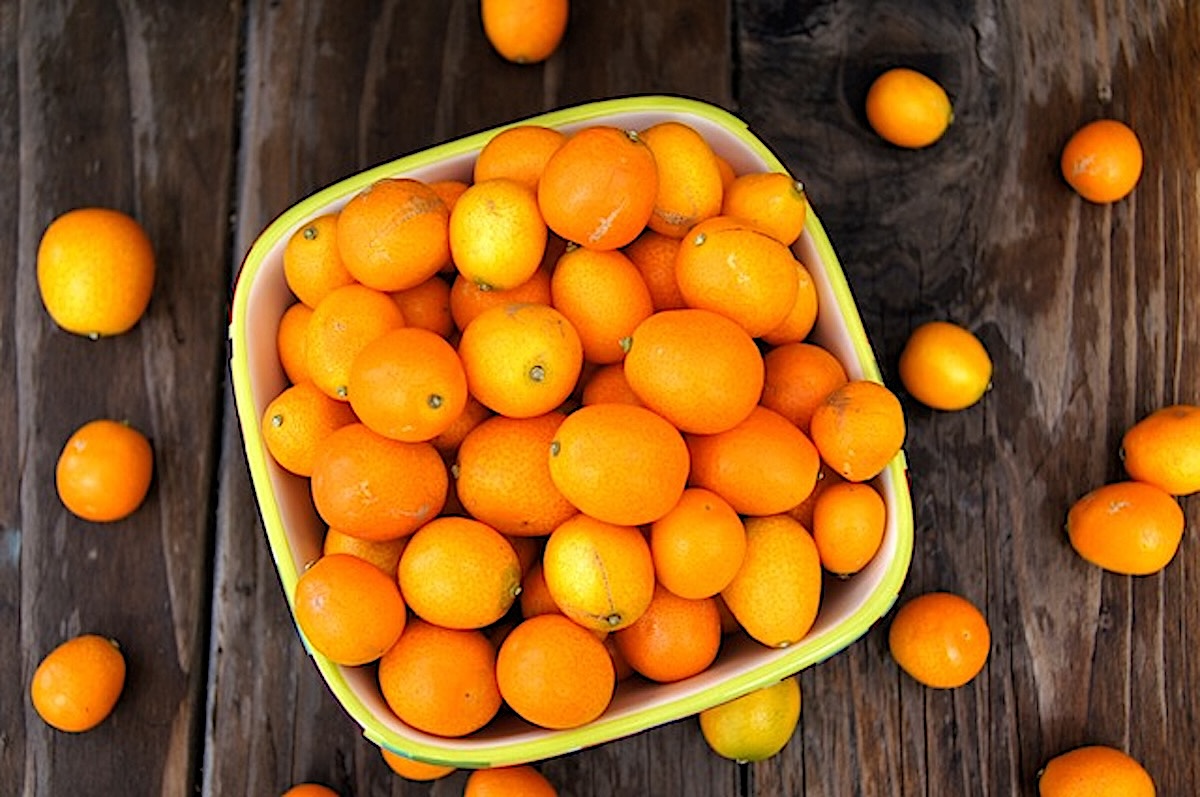 Kumquat-Marmalade-with-Ginger Square bowl full with fresh kumquats, with a few spilling on the table aroud it.