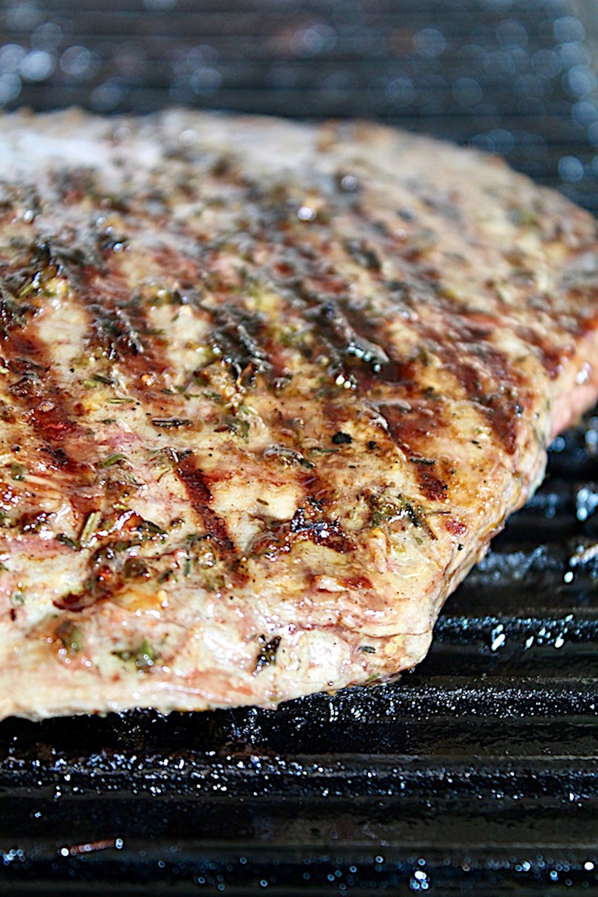 Mediterranean-Marinated-Flank-Steak Whole big piece of grilled flank steak with herbs on the stovetop grill.