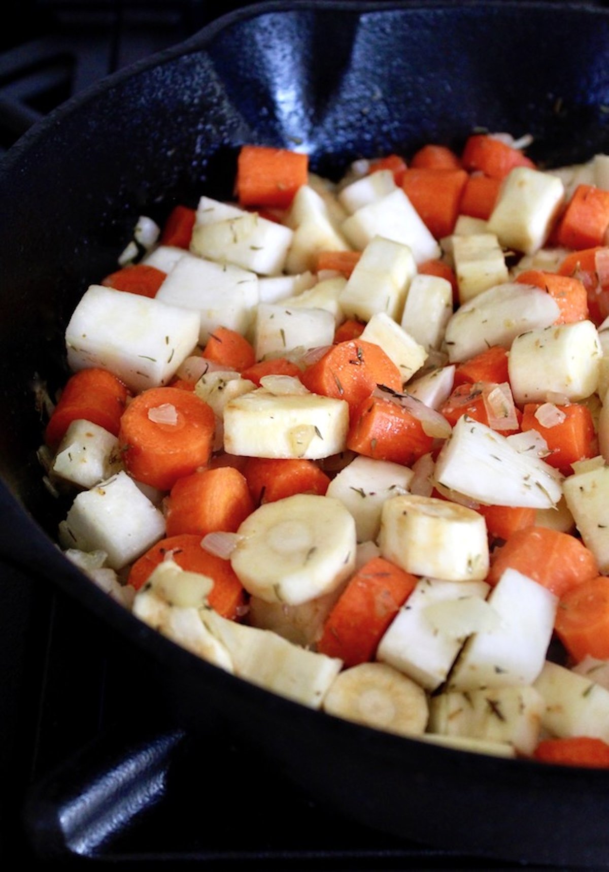 Root-Vegetable-Lasagna-with-Carrots Root vegetables in a cast iron skillet with fresh herbs.