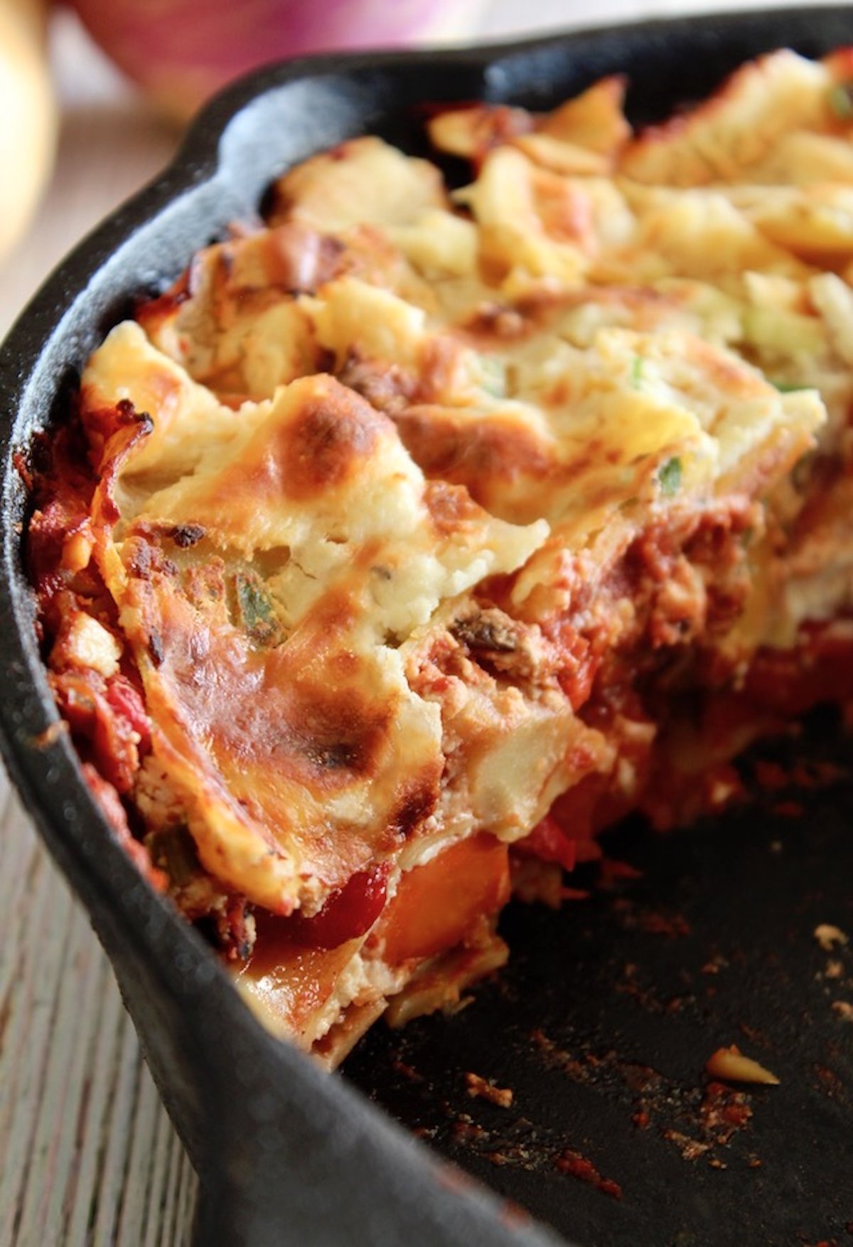 Root-Vegetable-Lasagna-with-Carrots Baked lasagna in a cast iron skillet with one slice taken out of it.