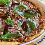 Green Pizza with fresh basil leaves on a yellow-rimmed plate.