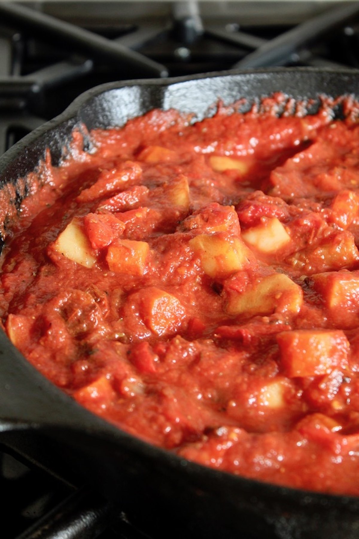 Root-Vegetable-Lasagna-with-Carrots Root vegetables in a cast iron skillet covered with tomato sauce.