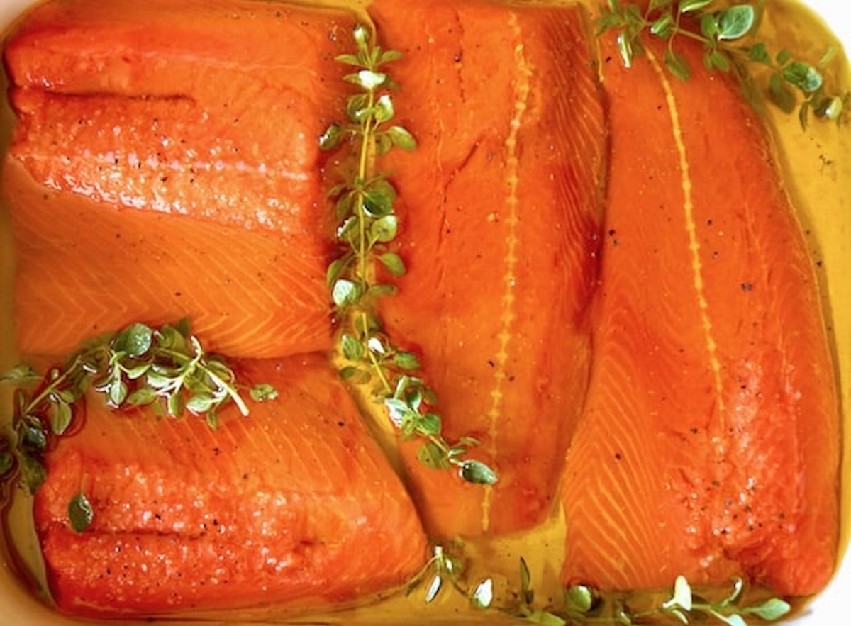 Salmon fillets in baking pan with thyme and olive oil.