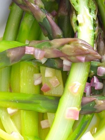 Peeled Purple Asparagus Recipe in a bright white dish with bits of shallots.