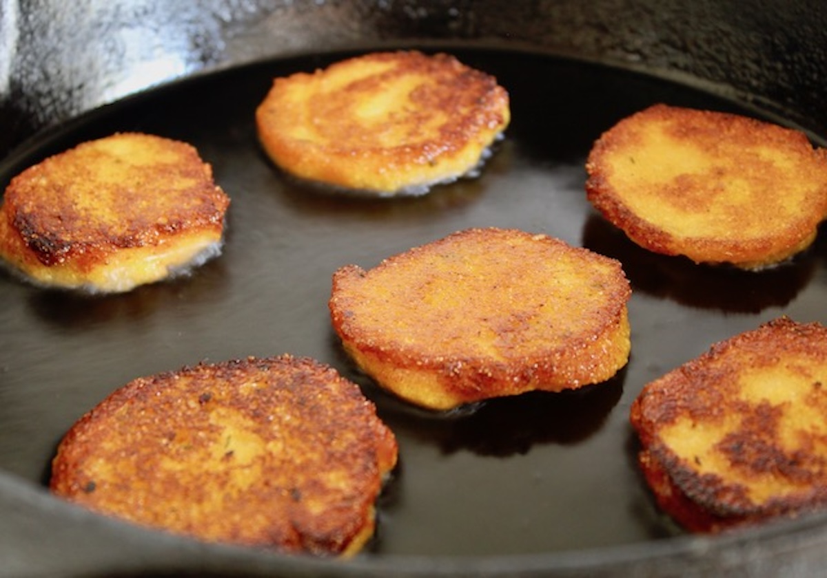 5 round golden brown hot water cornbreads in a skillet (looks like pancakes.)