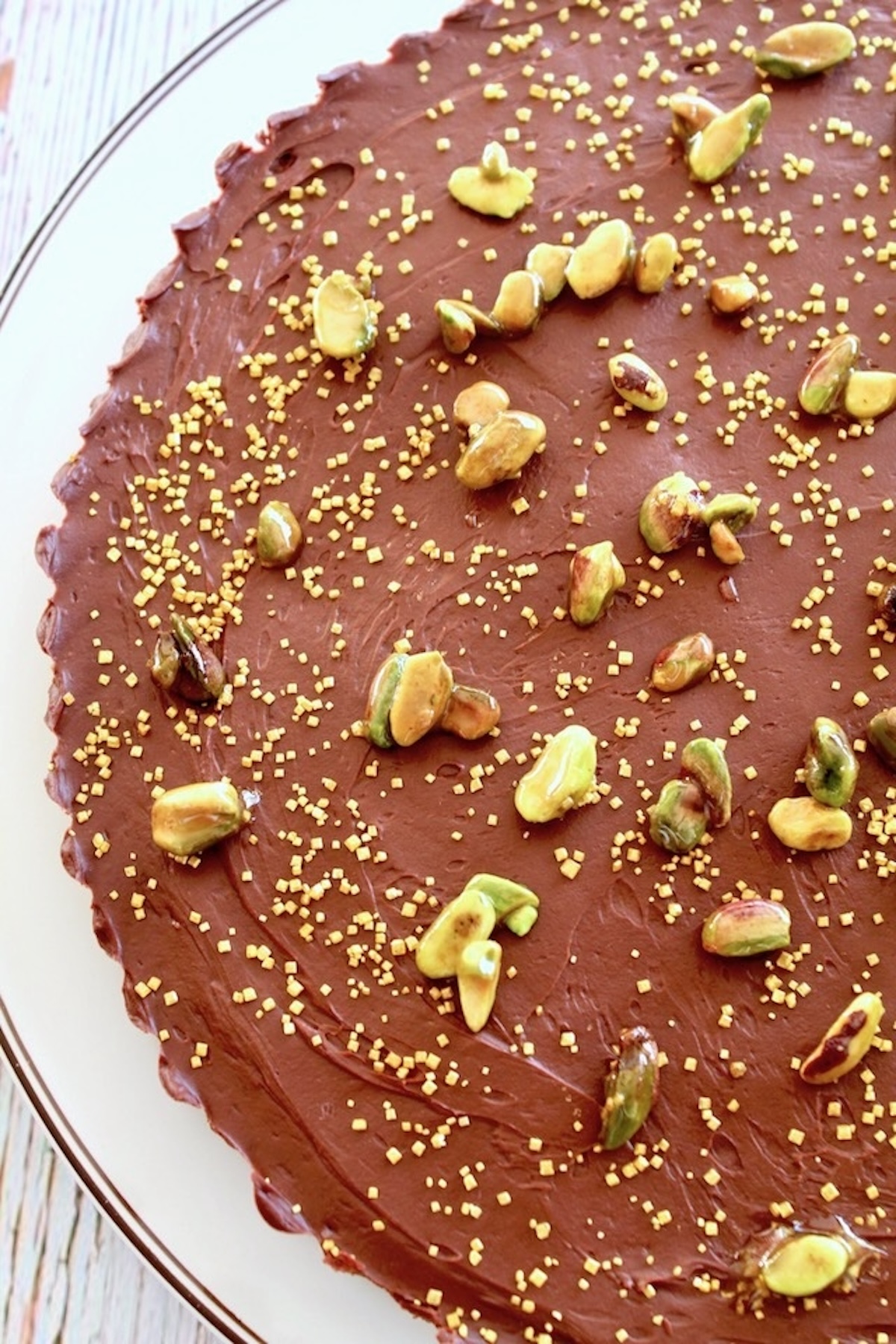 Chocolate-Tart-with-Pistachio-Crust Top view of Chocolate Pistachio tart on white platter.