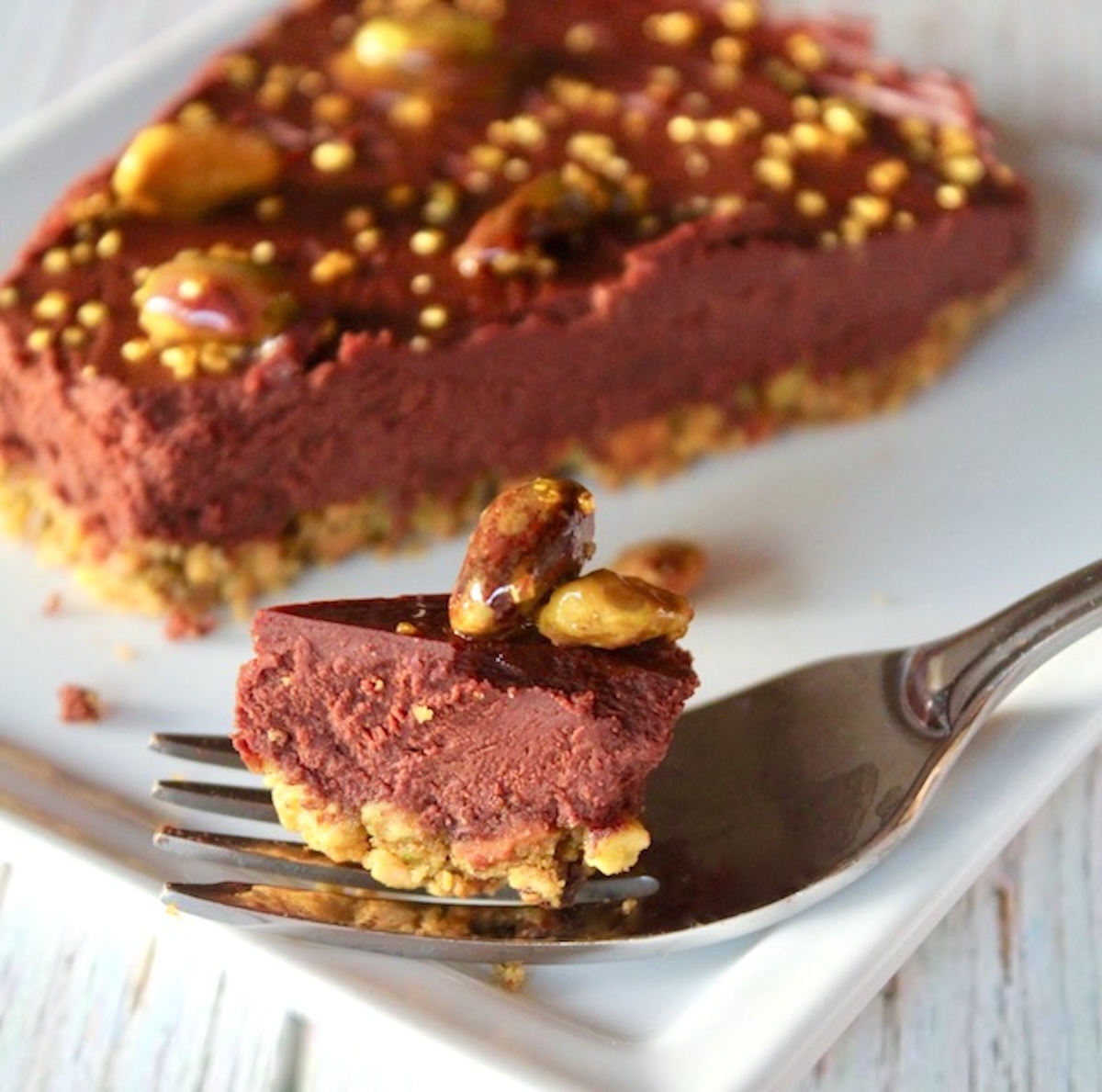 Chocolate-Yogurt-Tart-with-Pistachio-Crust Slice of chocolate, pistachio crusted tart with one bite in a fork.