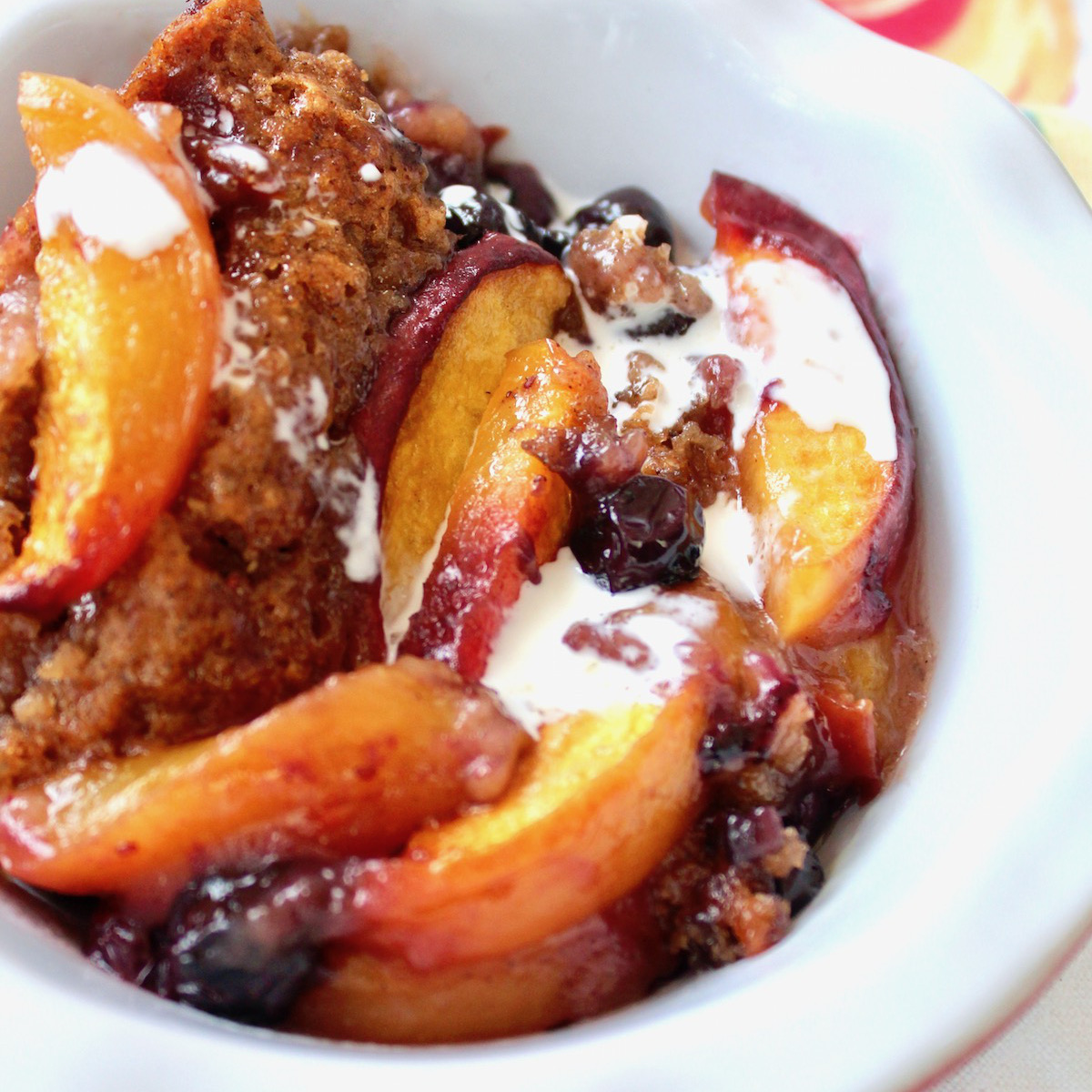 Peach-Cobbler-with-blueberries White bowl with peach cobber with blueberries and milk.