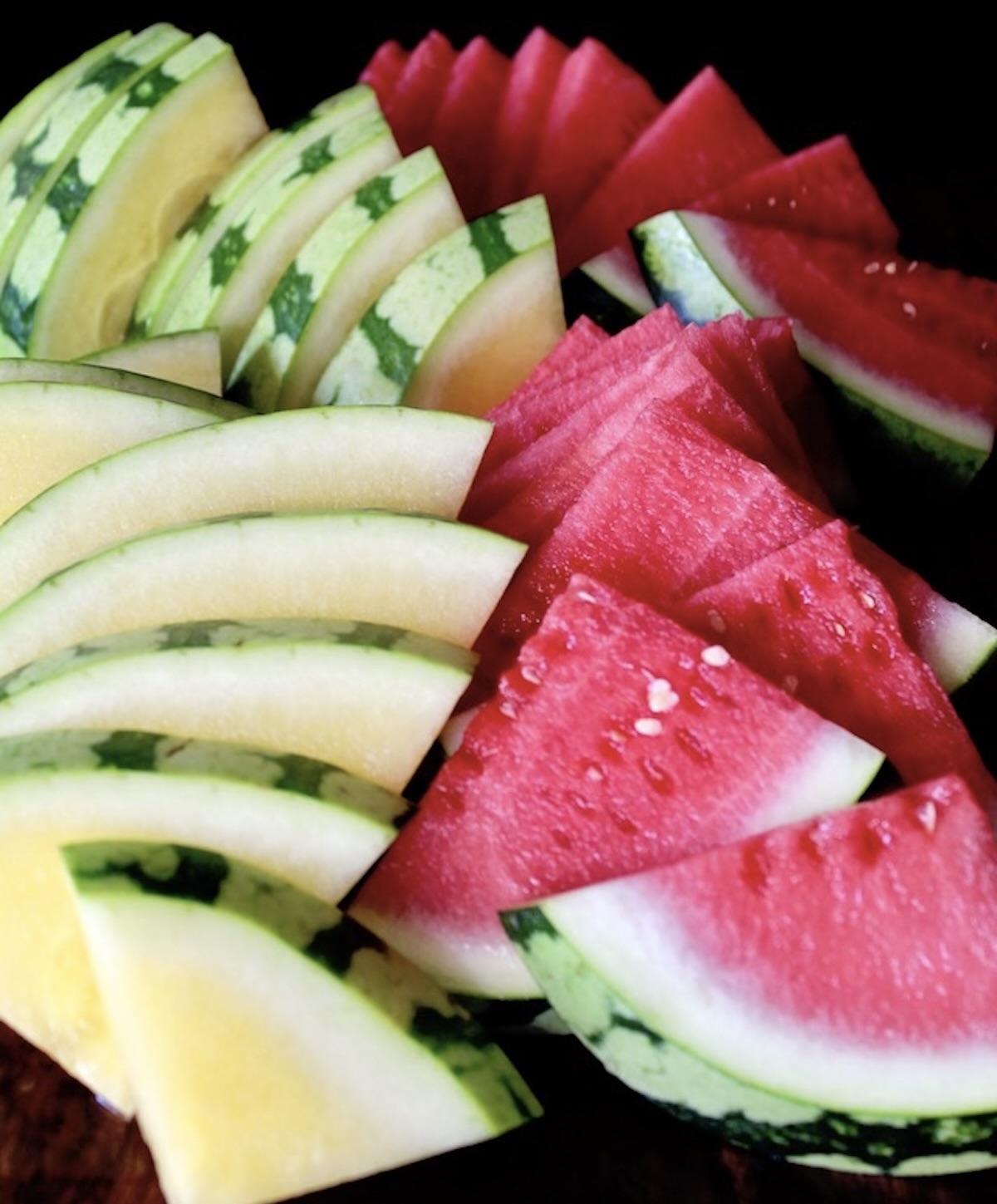 Lime-Chile-Grilled-Watermelon Slices of red and yellow watermelon on a black background.