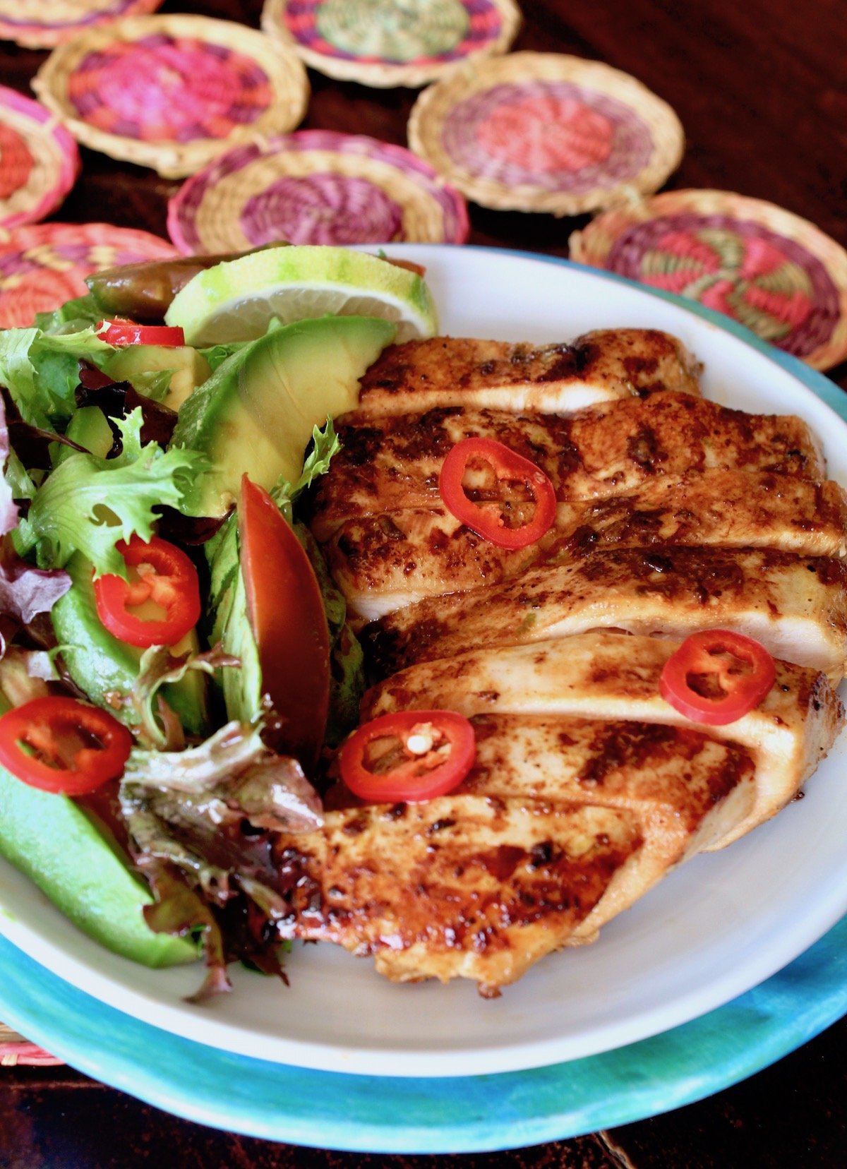 sliced tequila lime chicken on white plate with a side salad