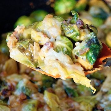 Cheesy brussels sprouts baked with pancetta, with a big orange spoon holding some of it up.