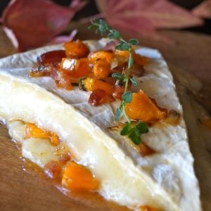 Persimmon brie appetizer on wood board.