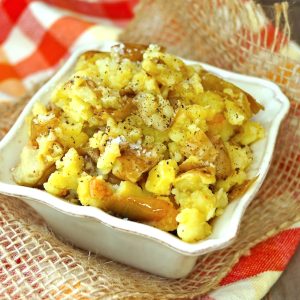 Rustic Garlic Confit Mashed Potatoes in a small, square white dish on a red, white and orange cloth napkin.