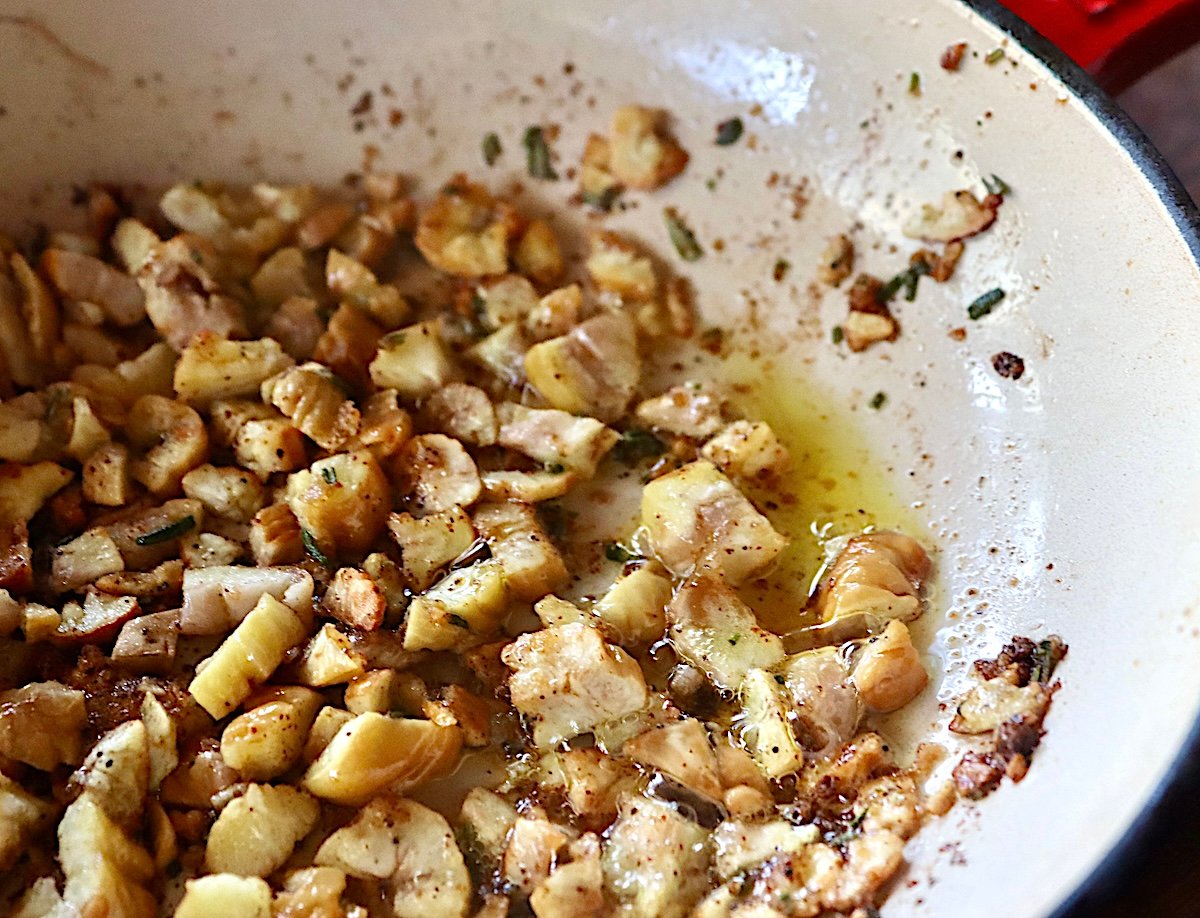 Roughly chopped chestnuts in a saute pan with olive oil, rosemary and spices.