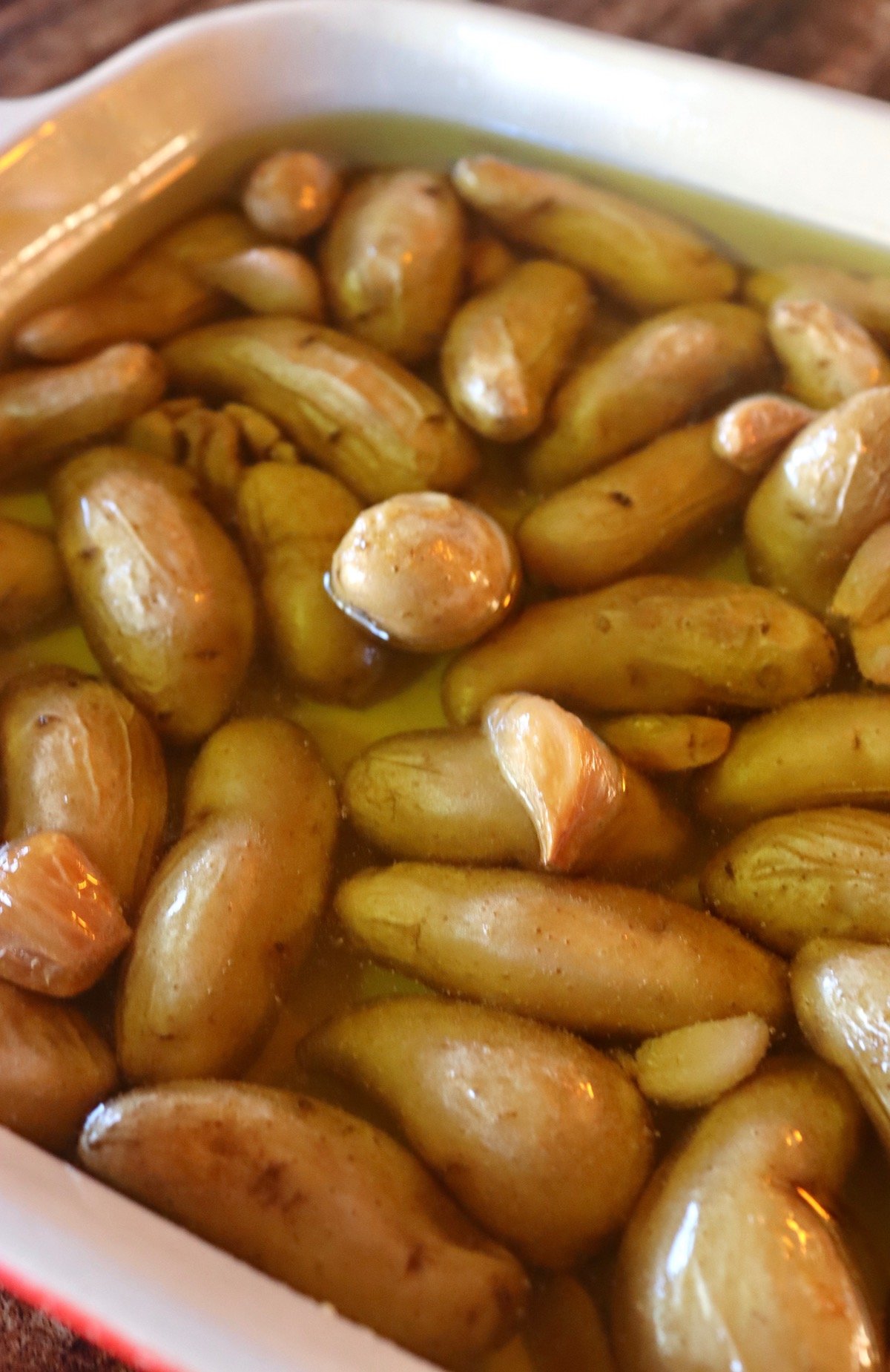 Potato Garlic Confit in a casserole dish with roasted garlic.