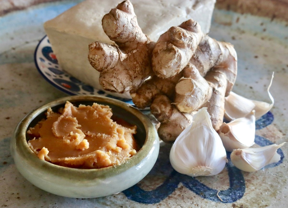 A few of the ingredients for Miso Tofu including Shiro miso, a few garlic cloves, fresh ginger and a block of tofu.